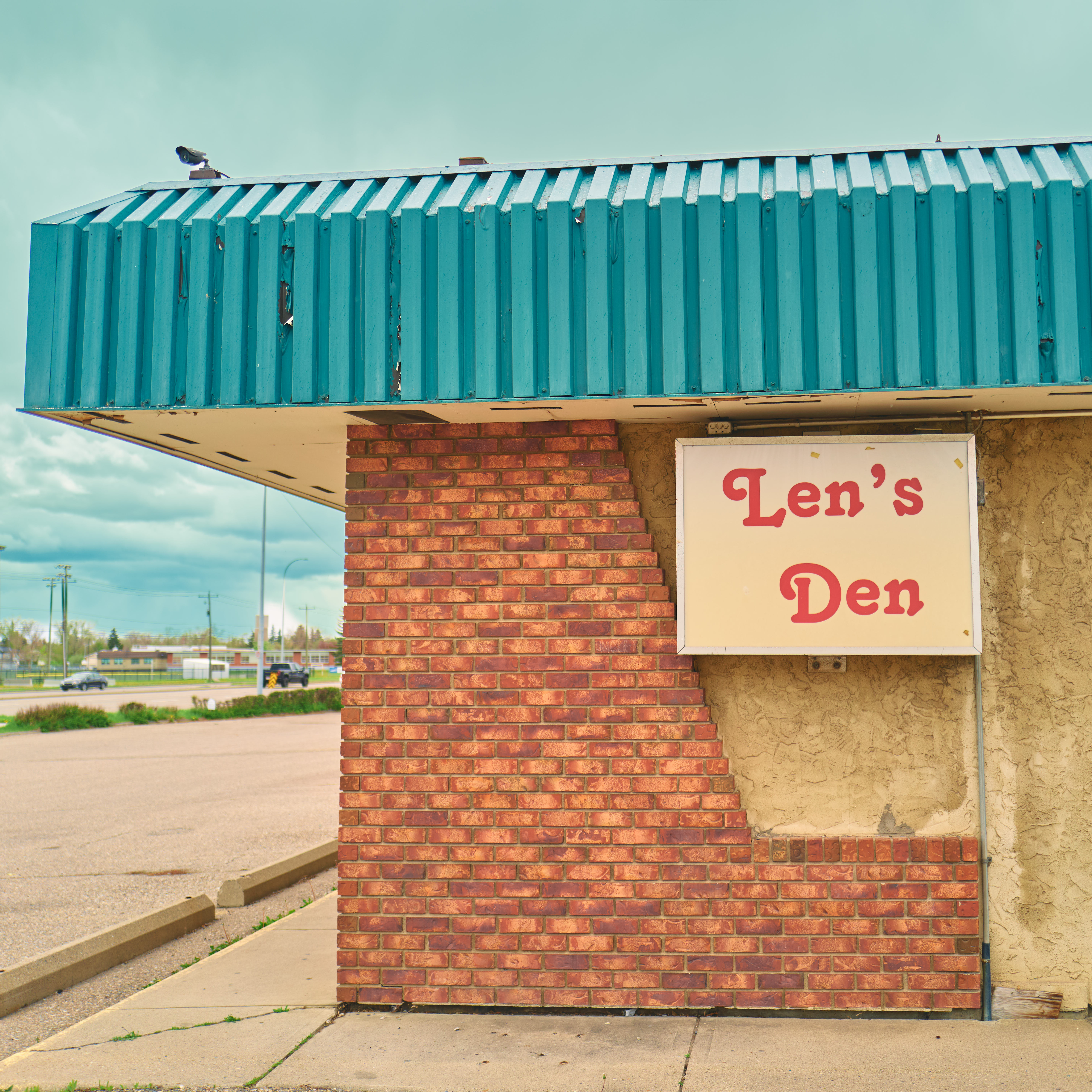 Len's Den vintage motel sign with teal awning and brick facade, small-town Alberta