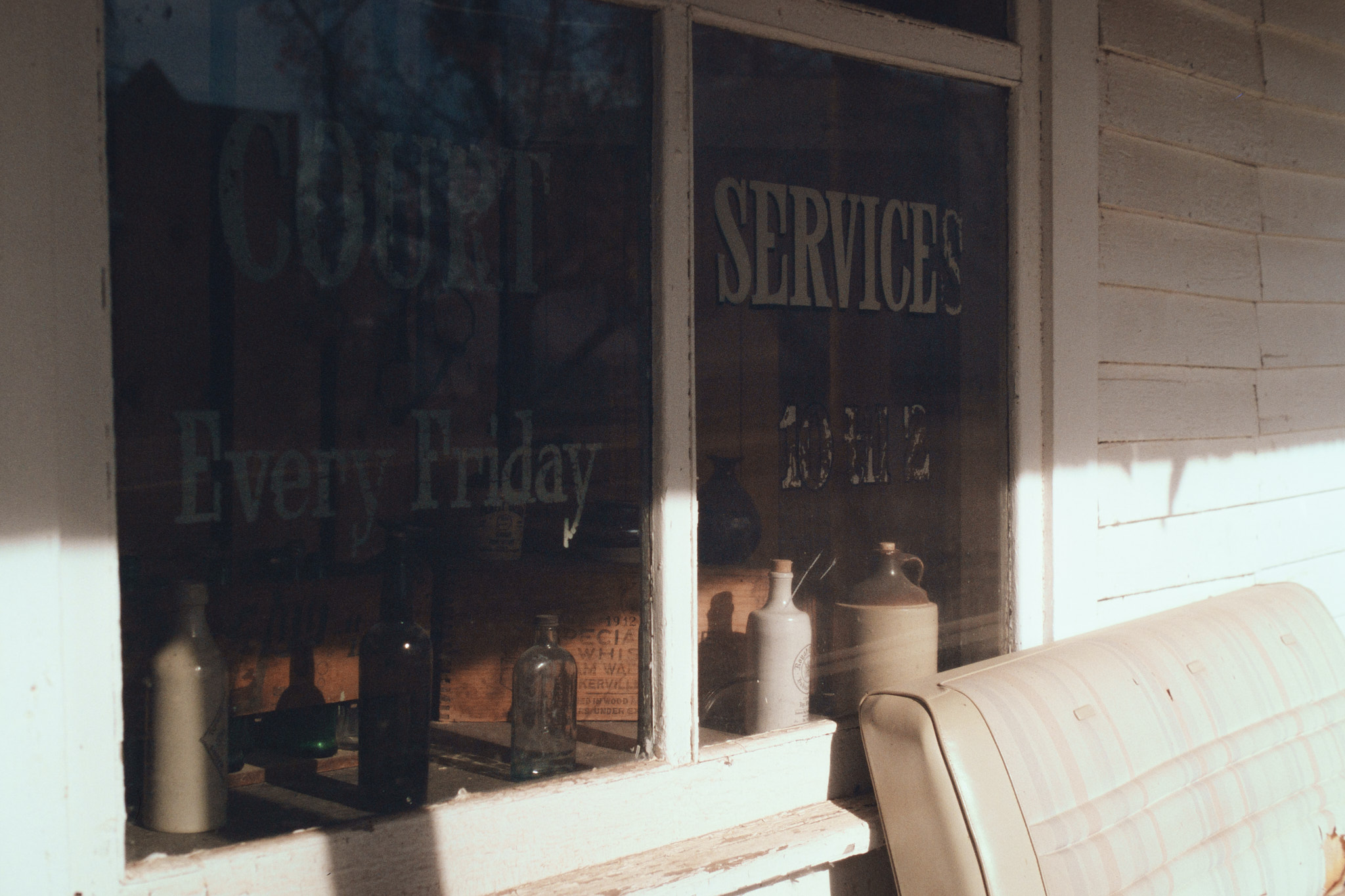Ghost town storefront window with old bottles and painted lettering, medium format film