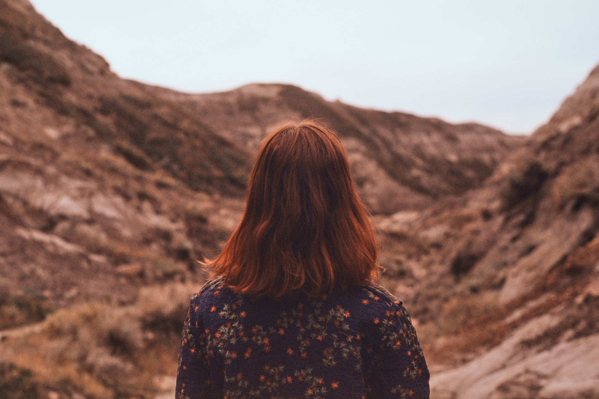 Woman seen from behind looking out over the Alberta badlands, medium format film