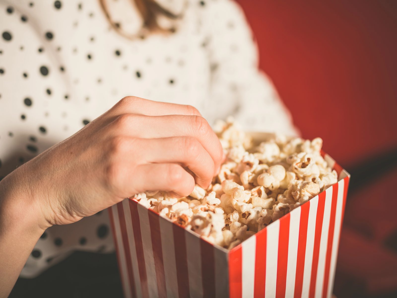 Woman eating popcorn from striped box — commercial lifestyle photography