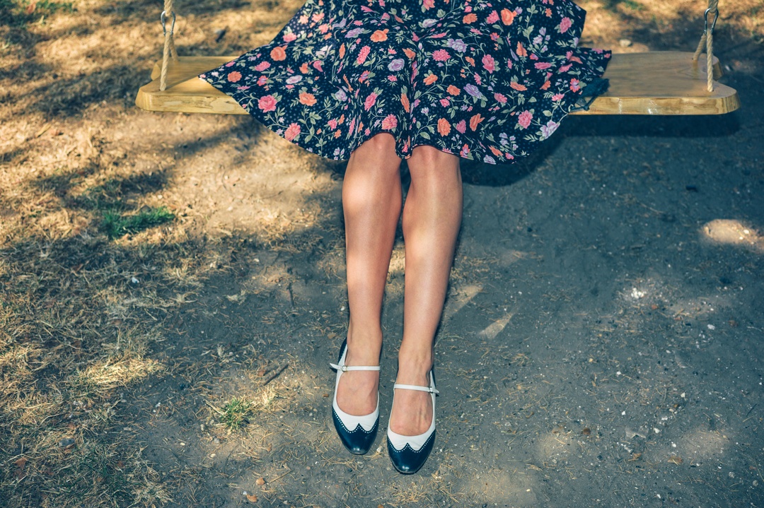 Legs on swing in floral dress and heels — vintage fashion detail photography