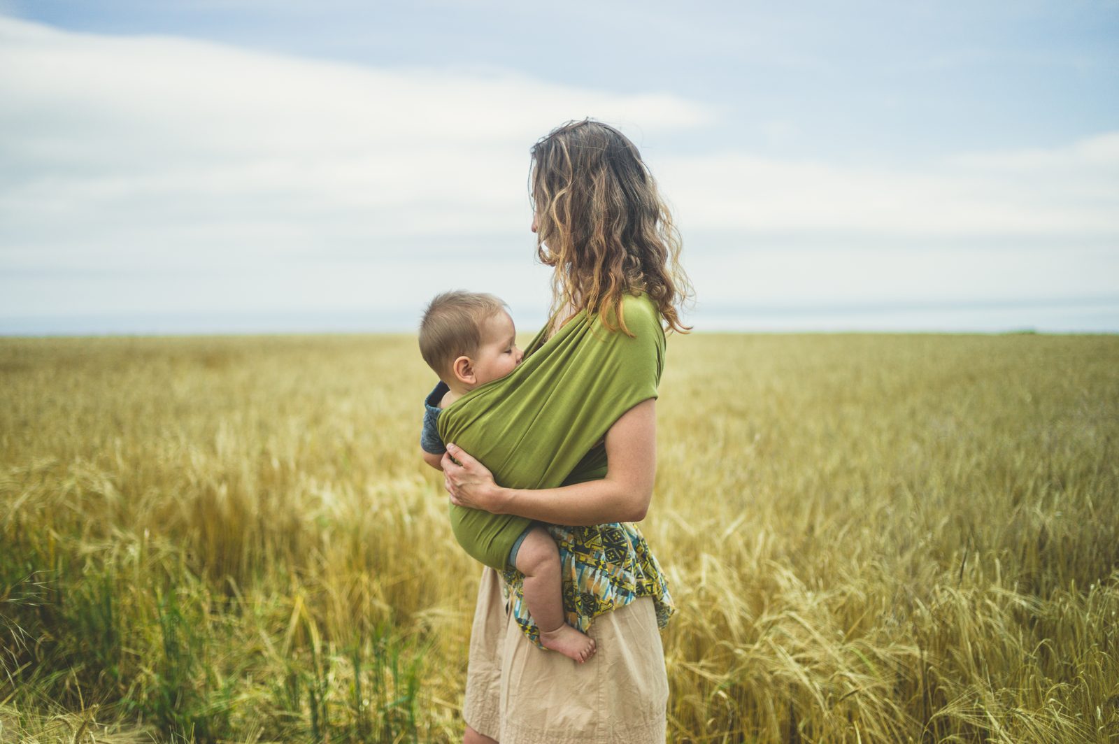 Mother with baby in sling in wheat field — family lifestyle photography