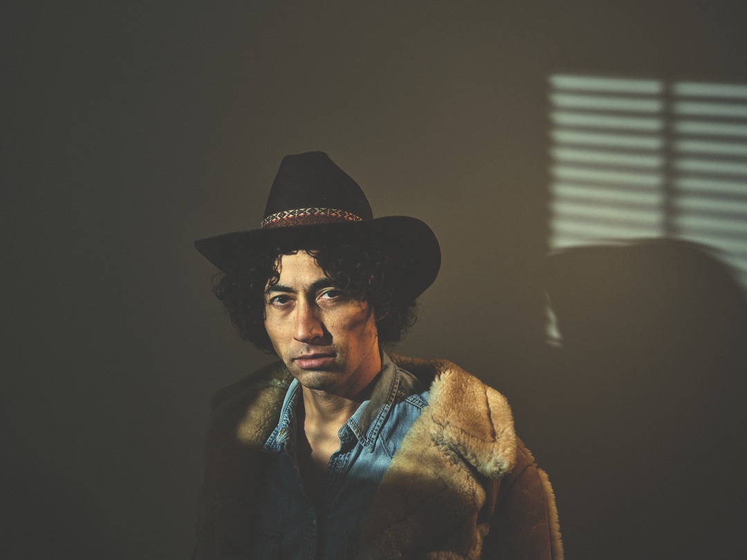 Portrait of man in hat with venetian blind shadows — moody natural light photography